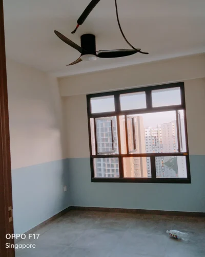 A freshly painted modern condo room featuring a two-tone blue and white wall, a black ceiling fan, and large framed windows overlooking city high-rises.