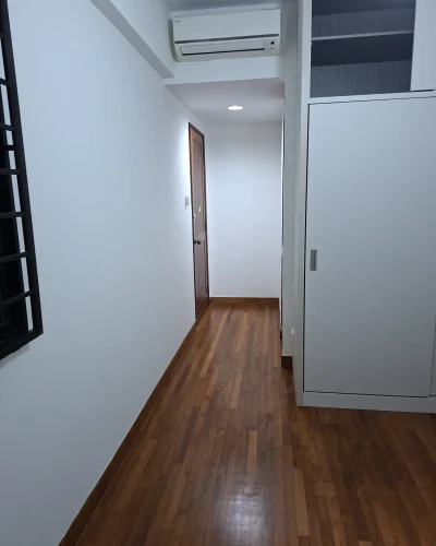A freshly repainted modern hallway featuring crisp white walls, rich hardwood floorboards, a wall-mounted air conditioner, and built-in white cabinetry.