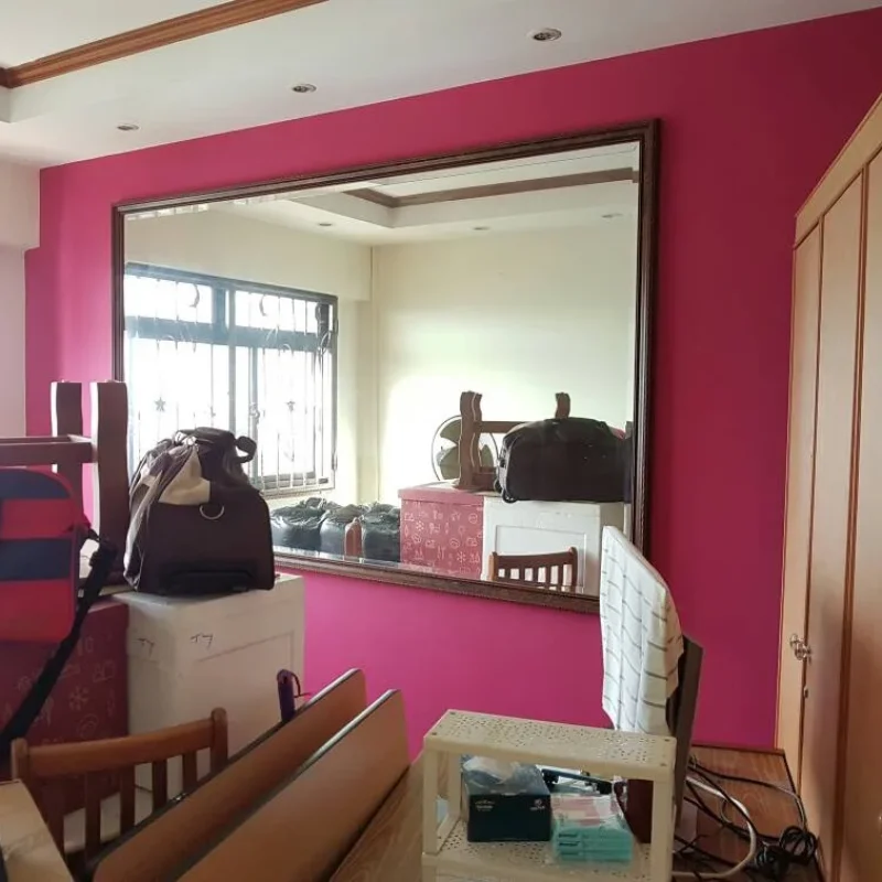 Interior view of a room with vibrant magenta accent wall, large framed mirror reflecting the room, recessed ceiling lights, and white ceiling in Singapore.