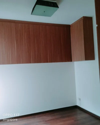 An interior room featuring upper wood-grain cabinets mounted against crisp white walls and dark wooden flooring.