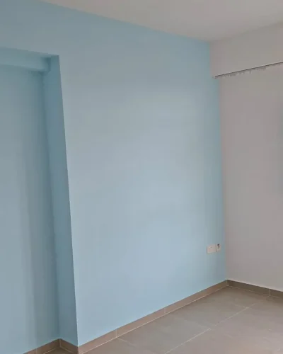 An empty room featuring a light blue feature wall, smooth white Interior Painting adjoining walls, tile flooring, and a large window with grilles.