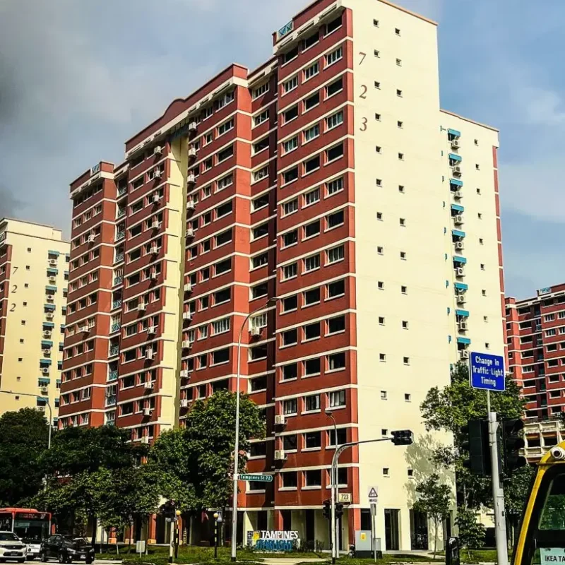 Exterior view of Block 723 HDB residential apartment building painted in red and beige tones along a street intersection in Singapore.