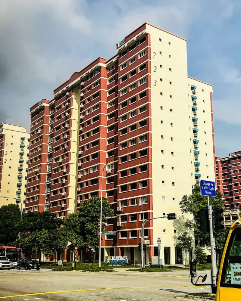 Exterior view of Block 723 HDB residential apartment building painted in red and beige tones along a street intersection in Singapore.